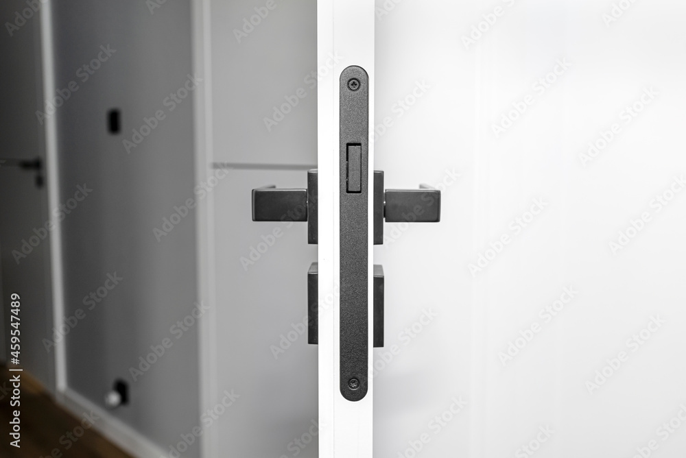 Modern white door with matte black handle and magnetic locks, lock with insert key. Modern white door with matte black handle and magnetic locks, lock with insert key.
