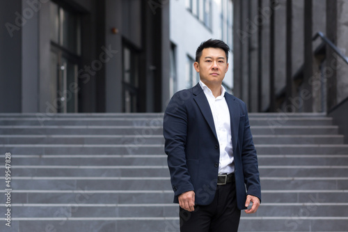 Portrait of asian serious businessman near office in business suit confident broker sales manager