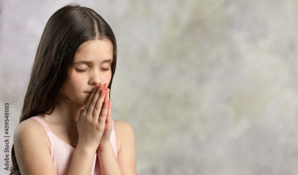 little child praying to God with hands together and a smile