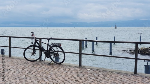 Bicycle leaning on a railing at the bobbled lake embankment.