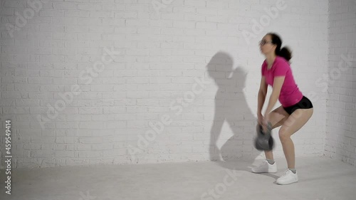 Young beautiful woman doing kettlebell swing. Fitness concept. Workout.