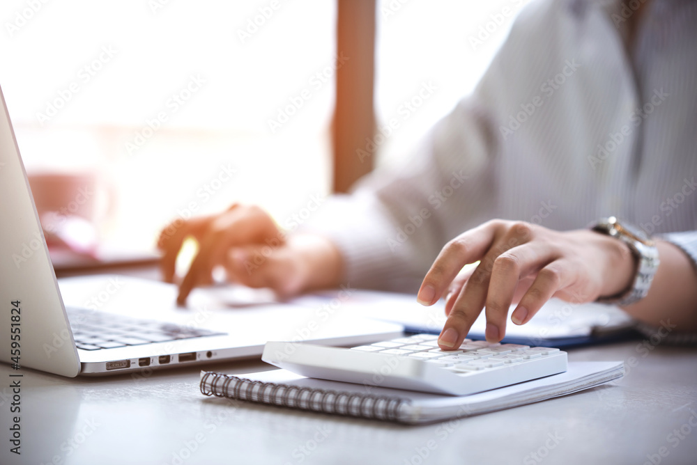 business woman or accountant who are using a calculator to calculate business data Accounting documents and laptop computer at the office business idea business woman or accountant who are using a calculator to calculate business data Accounting documents and laptop computer at the office business idea