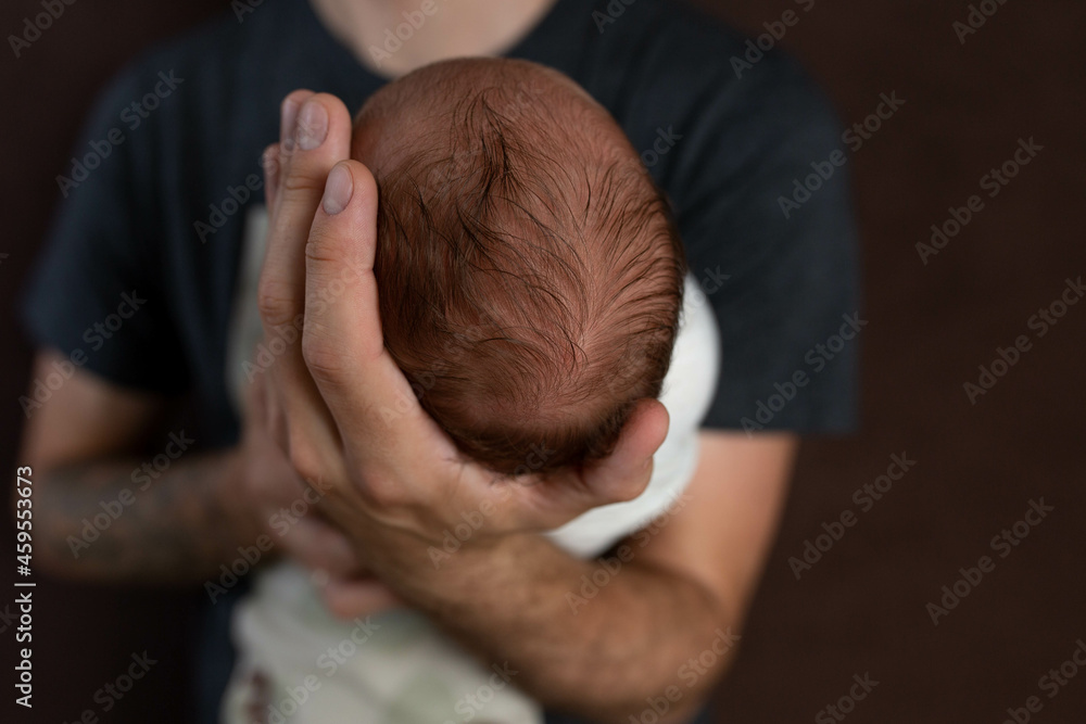 the head of a newborn daughter in the palm of a father. small head of newborn the head of a newborn daughter in the palm of a father. small head of newborn