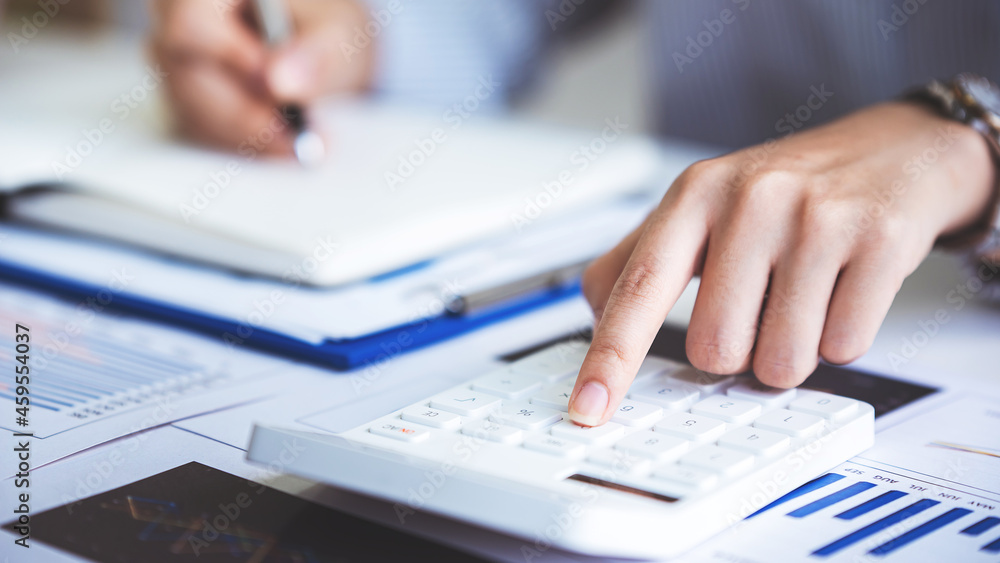 Fototapeta premium business woman or accountant who are using a calculator to calculate business data Accounting documents and laptop computer at the office business idea