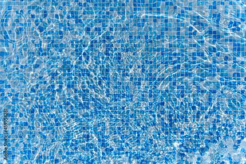 Swimming pool mosaic bottom caustics ripple like sea water and flow with waves background with sun light reflection
