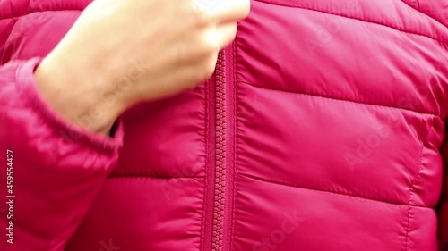 female hand zipper on red winter warm jacket, zipper on clothes, dress up photo