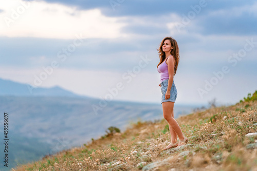 Beautiful slender woman on top of a mountain at sunset. Amazing landscape with a gradient of mountains. The concept of sports and active life.