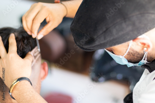 Barber using face mask, doing Highborn and freestyle by hand. Concept advertising barber shop