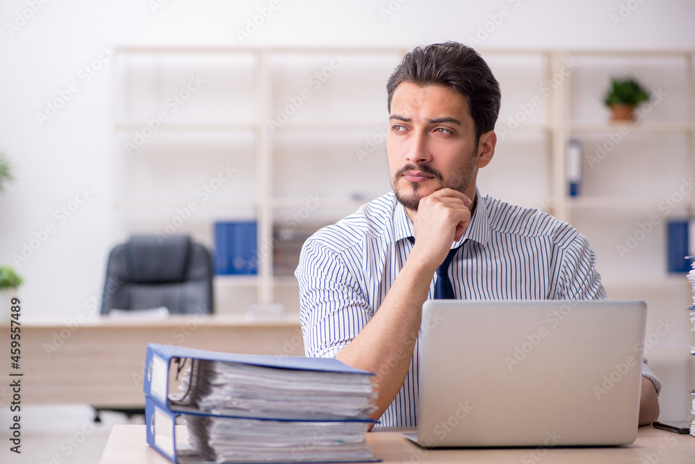 Young male employee and too much work in the office Young male employee and too much work in the office