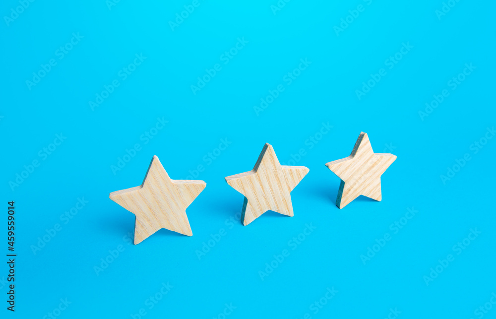 Obraz premium Three stars on a blue background. Rating evaluation concept. Service quality. Buyer feedback. High satisfaction. Popularity rating of a restaurant, hotel or mobile applications. Good reputation status