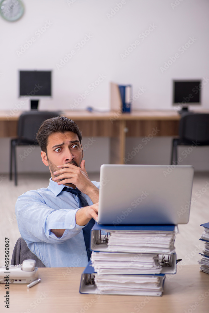 Young male employee and too much work in the office Young male employee and too much work in the office