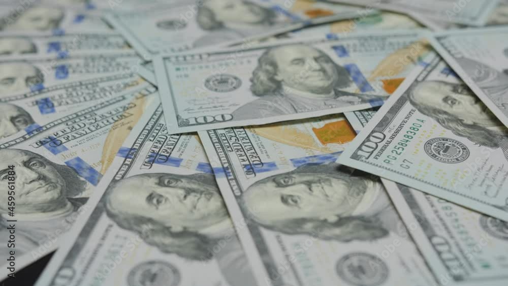 Pile of US currency banknotes are spinning on table, close up. Dollar bills rotating. Background with money american hundred USD dollar bills. Pile of US currency banknotes are spinning on table, close up. Dollar bills rotating. Background with money american hundred USD dollar bills.