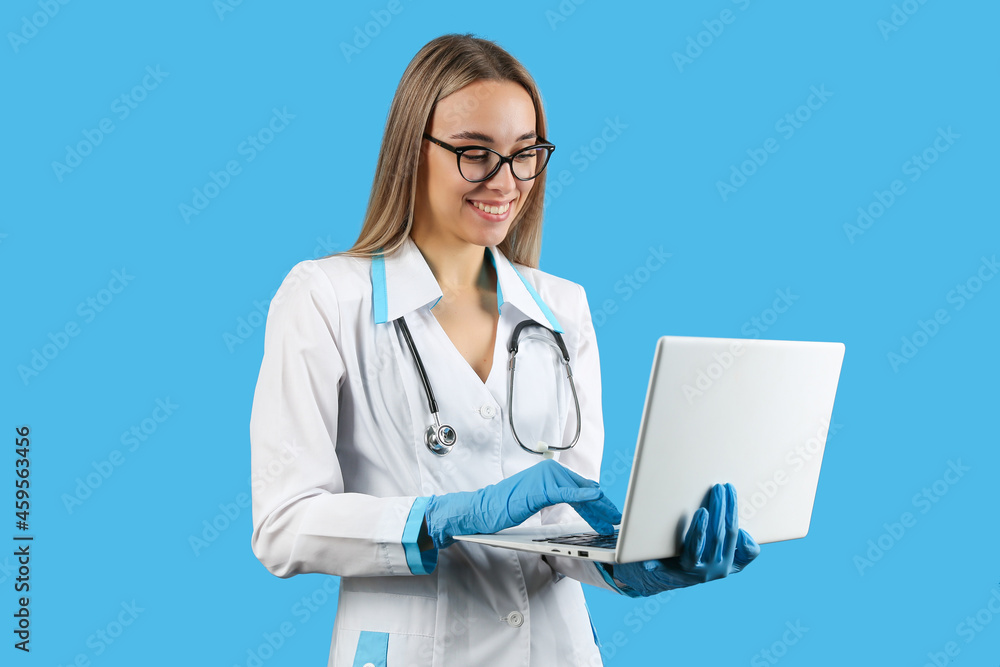 beautiful doctor woman holding laptop on blue background, studio shot. concept of telemedicine beautiful doctor woman holding laptop on blue background, studio shot. concept of telemedicine