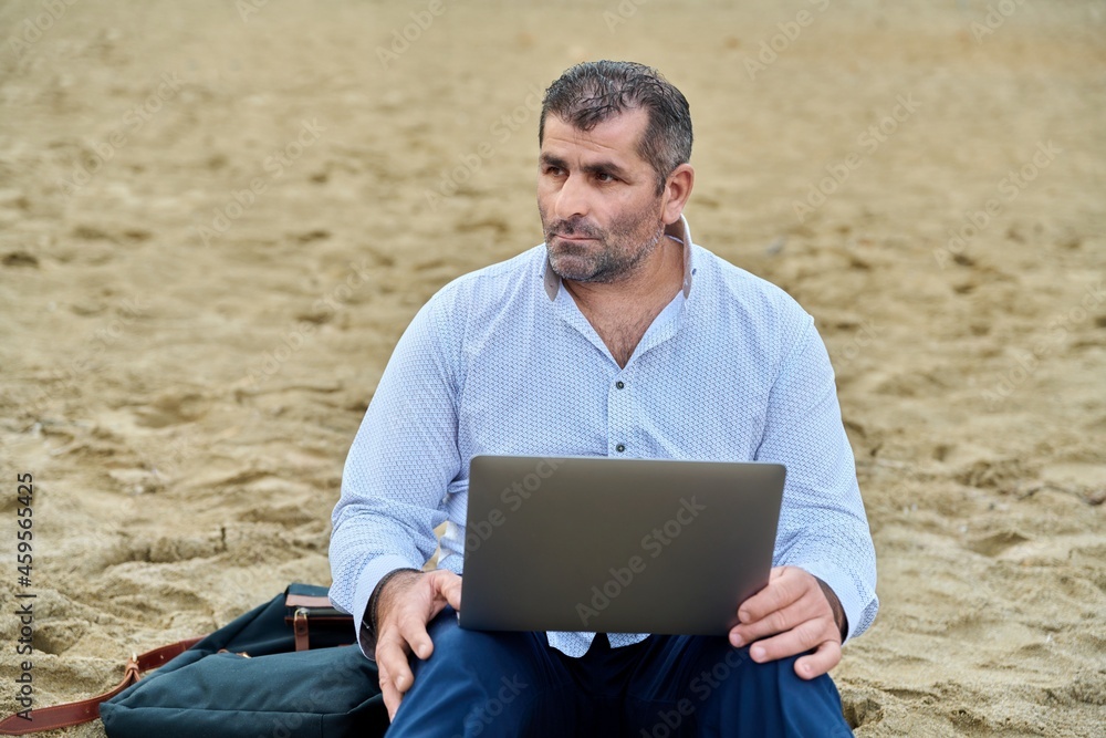 Serious confident mature man with laptop outdoors Serious confident mature man with laptop outdoors