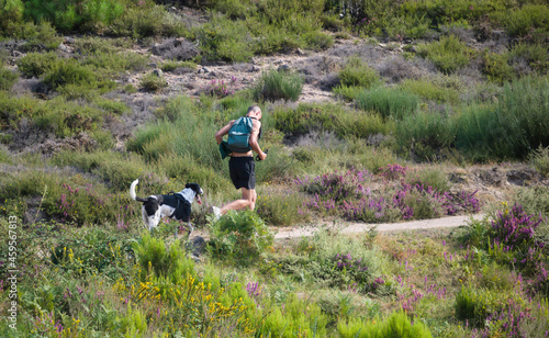 Jovem rapaz a correr num trilho de montanha com um cão ao lado - trail running - mascote photo