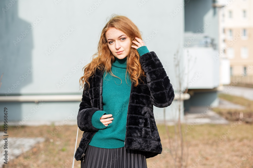 A beautiful tall woman walks in a long skirt and a green sweater. Autumn in the city.