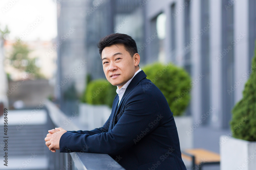 worker salesman asian businessman, on the balcony of a modern office center, man in a business suit cheerful and happy smiling worker salesman asian businessman, on the balcony of a modern office center, man in a business suit cheerful and happy smiling