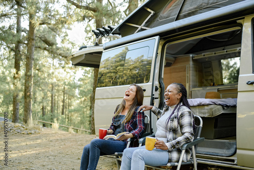 Multiracial traveling women laughing near camper