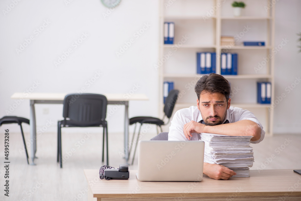 Young male employee and too much work in the office Young male employee and too much work in the office
