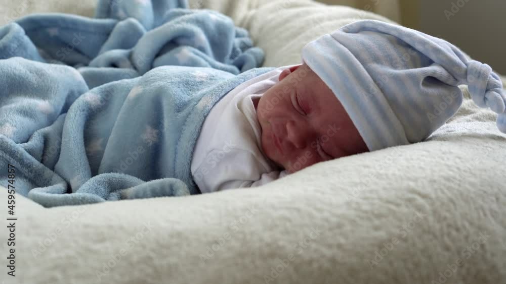 Close-up Newborn Baby Face Portrait Early Days Sleeping Sweetly On Tummy Blue White Background. Child At Start Minutes Of Life on Hat. Infants, Childbirth, First Moments Of Borning, Beginning Concept Close-up Newborn Baby Face Portrait Early Days Sleeping Sweetly On Tummy Blue White Background. Child At Start Minutes Of Life on Hat. Infants, Childbirth, First Moments Of Borning, Beginning Concept