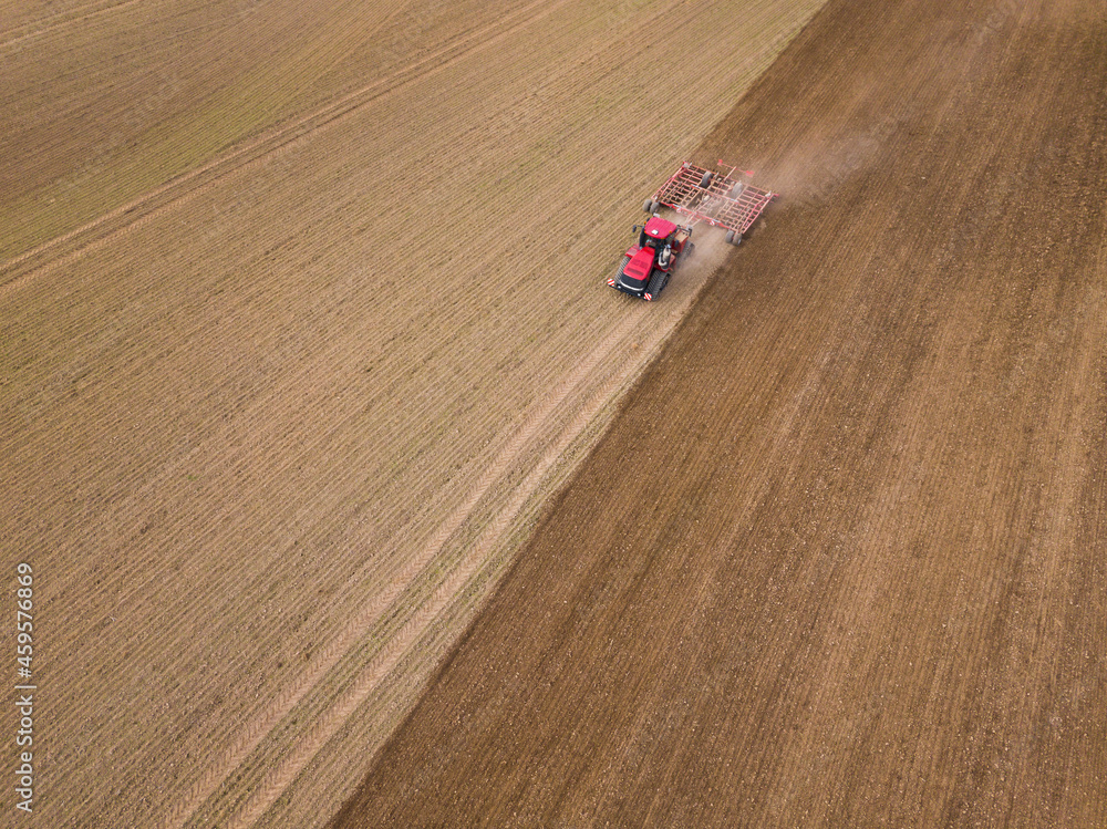 Aerial photo of a tractor ploughing stubble field in countryside. Agricultural tractor plows soil field for sowing. Aerial top view from the drone . Autumn farming concept. Land cultivation
