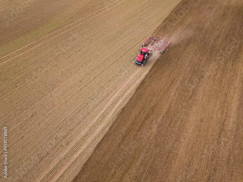 Aerial photo of a tractor ploughing stubble field in countryside. Agricultural tractor plows soil field for sowing. Aerial top view from the drone . Autumn farming concept. Land cultivation 