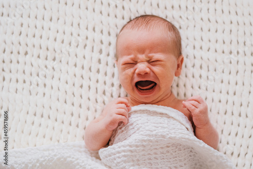 Closeup portrait of crying newborn baby boy. Soft focus.