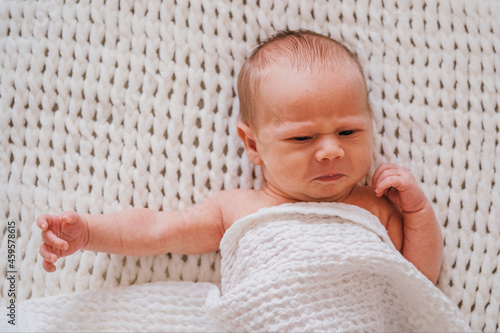 Closeup portrait of angry newborn baby boy. Soft focus.