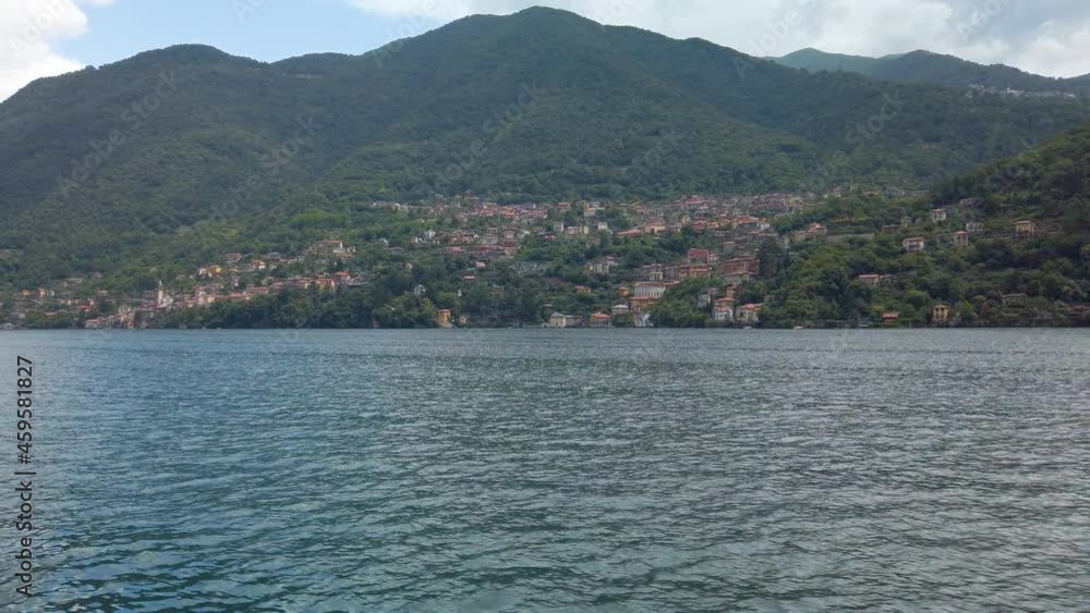 Passing small beautiful village in Lake Como. Village is seen from the lakeside. There are boats docked various places. It is a beautiful sunny summer day. 4K Passing small beautiful village in Lake Como. Village is seen from the lakeside. There are boats docked various places. It is a beautiful sunny summer day. 4K