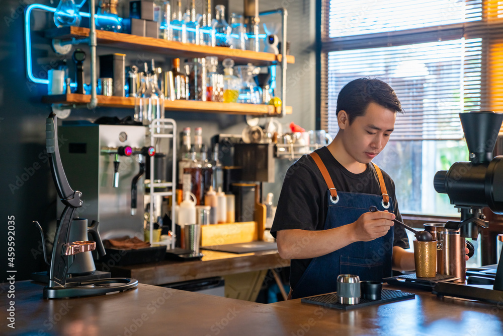 Asian man barista using coffee grinder machine grinding roasted coffee beans at cafe. Male coffee shop owner brewing black coffee serving to customer. Small business restaurant food and drink concept Asian man barista using coffee grinder machine grinding roasted coffee beans at cafe. Male coffee shop owner brewing black coffee serving to customer. Small business restaurant food and drink concept