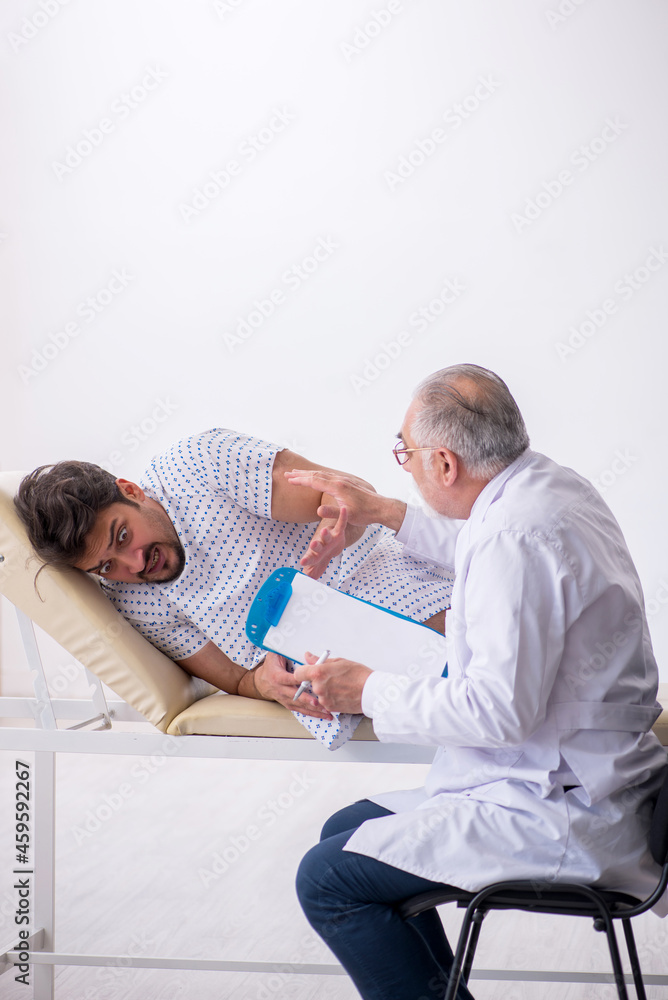 Old male doctor psychiatrist examining young male patient Old male doctor psychiatrist examining young male patient