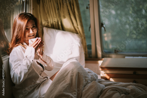 morning, coziness, winter and people concept - close up of happy young woman with cup of coffee or cocoa drink in bed