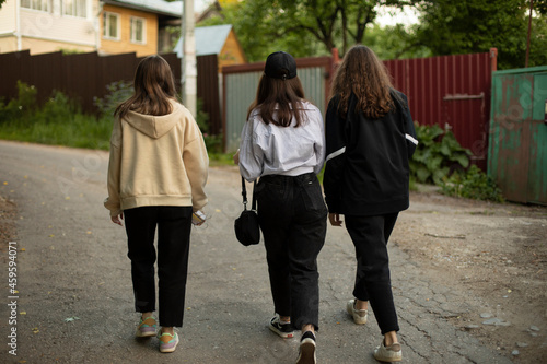 Three girls are walking down the road. Teenagers in the countryside.