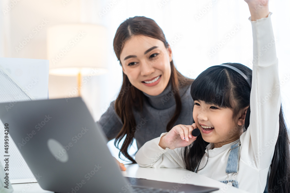 Asian little young girl kid learning online class at home with mother. Asian little young girl kid learning online class at home with mother.