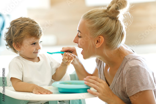 Mom feeds the baby. Young woman feeds her baby in the kitchen. High quality photo