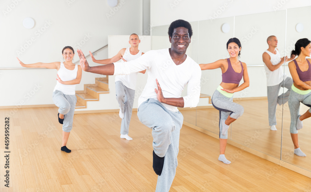 Portrait of dancing African-American practicing vigorous swing during group training in dance studio.