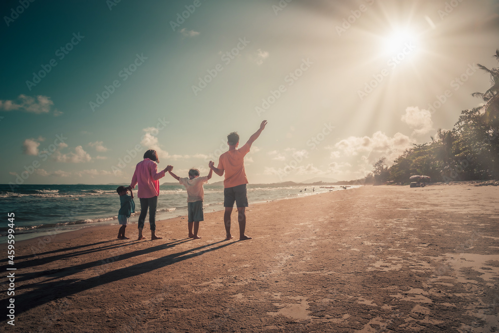 Happy family on the beach against blue sea and sky background at sunset. Holiday and summer travel concept