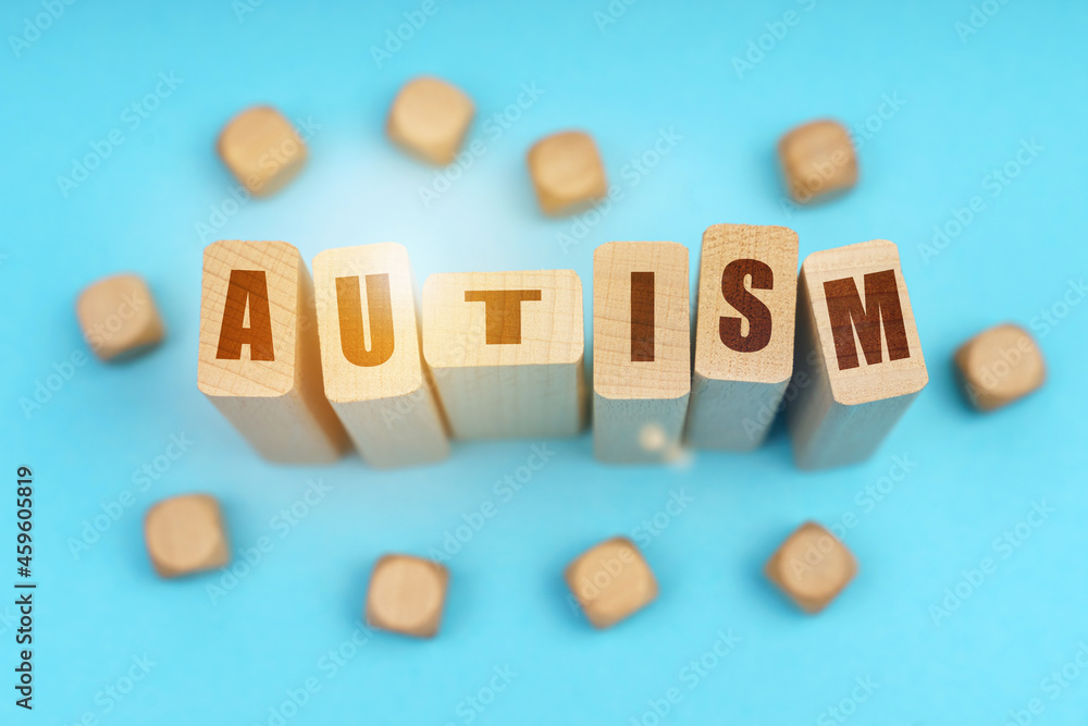 On a blue background, wooden cubes and Jenga with the inscription - AUTISM On a blue background, wooden cubes and Jenga with the inscription - AUTISM
