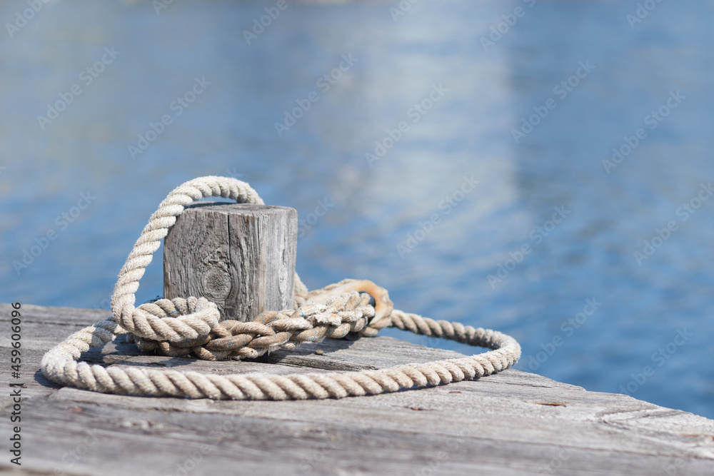 Naklejka premium A mooring line around a bollard on a wooden pier