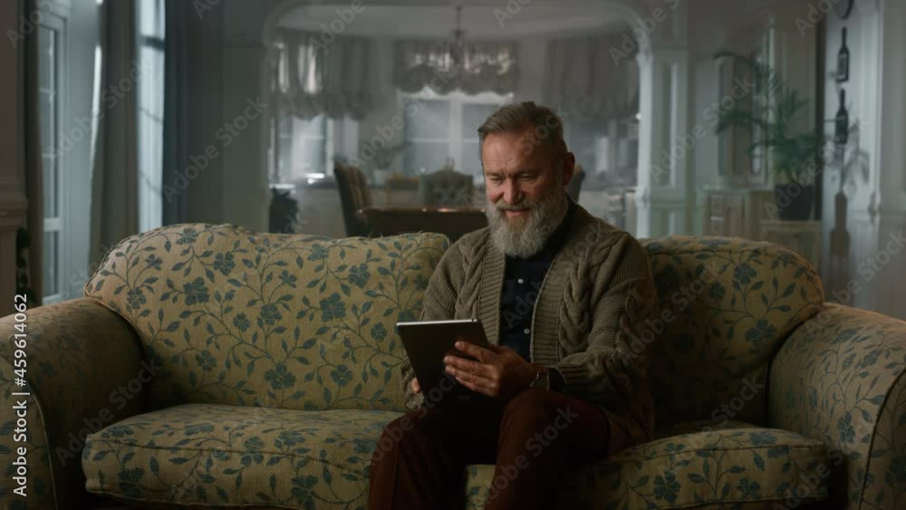 Calm senior man using tablet computer on sofa. Retired grandfather pad Calm senior man using tablet computer on sofa. Retired grandfather pad