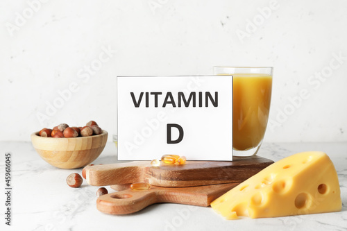 Text VITAMIN D and different healthy products on light background