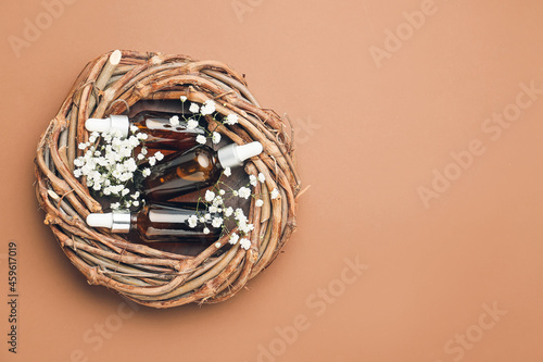 Nest with bottles of healthy essential oil on color background