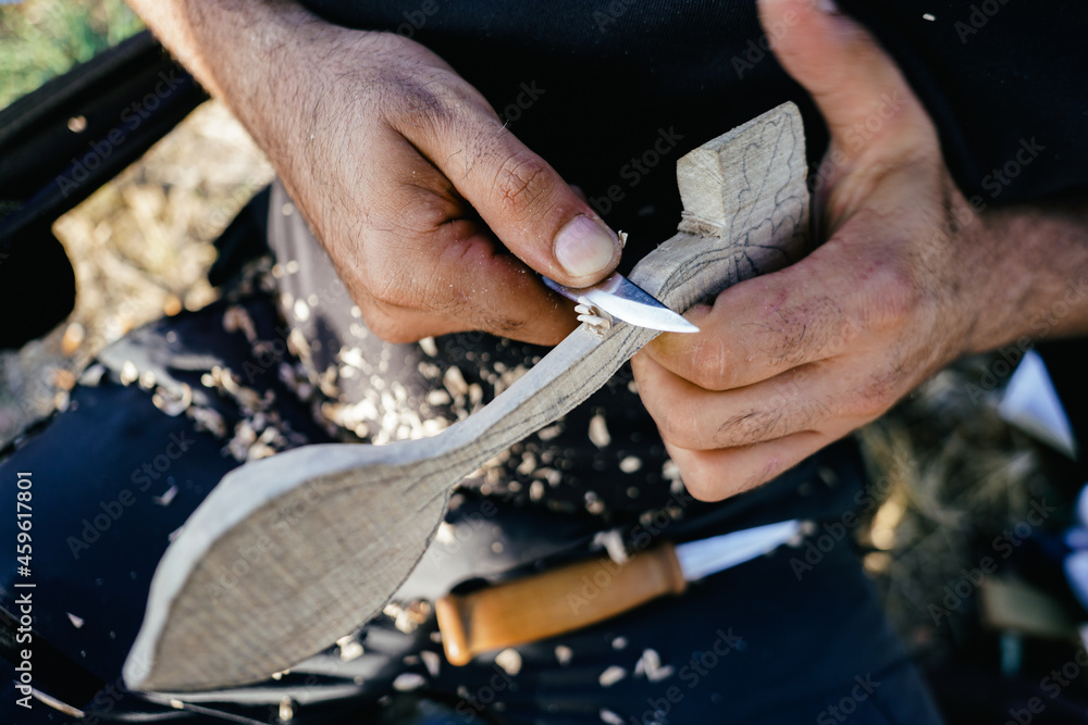 Close up of man carving branch with knife in nature Close up of man carving branch with knife in nature
