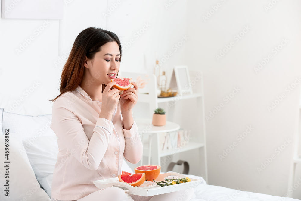 Morning of young Asian woman eating grapefruit in bedroom Morning of young Asian woman eating grapefruit in bedroom