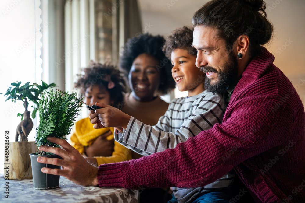 Happy multiethnic family at home taking care for flowers and having fun time together