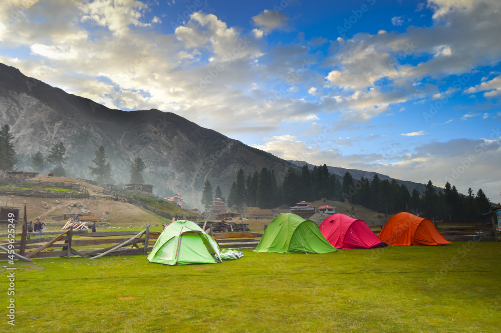 Camping Tents for tourists of different colors set over green grassy meadows in a tourist in Pakistan. Varrious colored  camping tents places over green ground in Paksitan