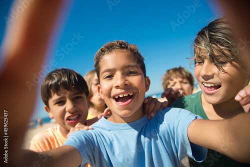 Selfie of cheerful multiethnic preteen boy friends. Portrait of happy kids on beach. Summer vacation and friendship concept
