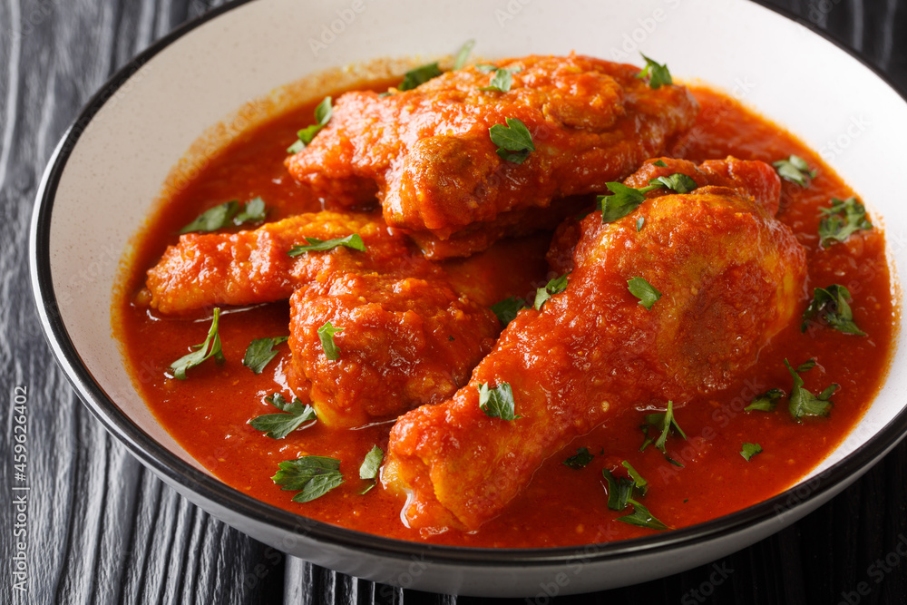 Ayam masak merah is a Malaysian dish made with chicken pieces that are doused in a rich, spicy, and creamy tomato sauce close-up in a bowl on the table. Horizontal