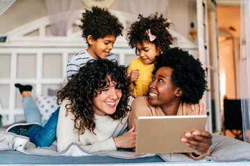 Family children gay parents concept. Happy multiethnic women couple having fun with kids at home