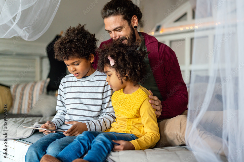 Multiethnic family happiness concept. Happy father and children using tablet and having fun at home